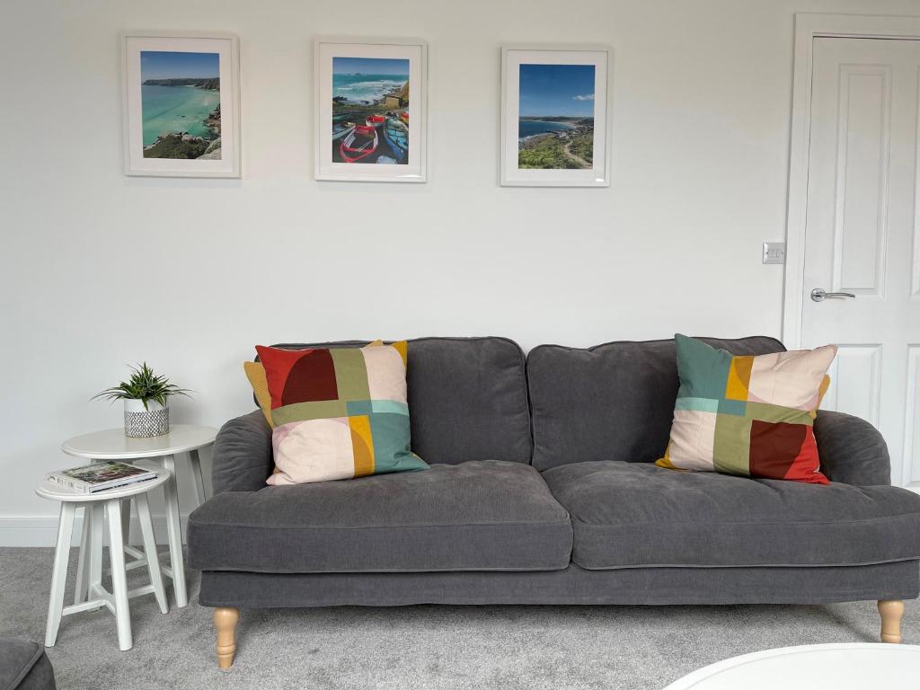 a grey couch in a living room with pictures on the wall at Stunning Town Centre Penthouse w/ Sea Views in Penzance