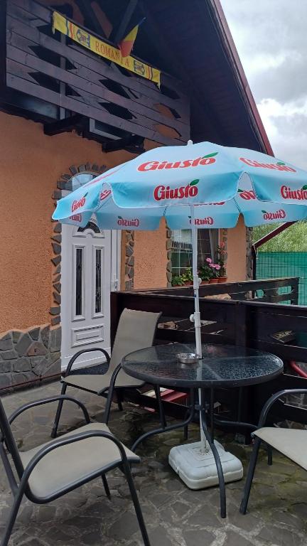 einen Tisch und Stühle mit Sonnenschirm auf einer Terrasse in der Unterkunft Casa Crivimex in Azuga