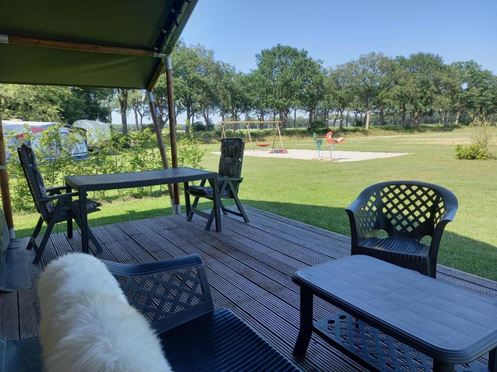 een houten terras met stoelen en een tafel en een picknicktafel bij Comfort Safaritent Jungle - 6 personen in Zwiggelte