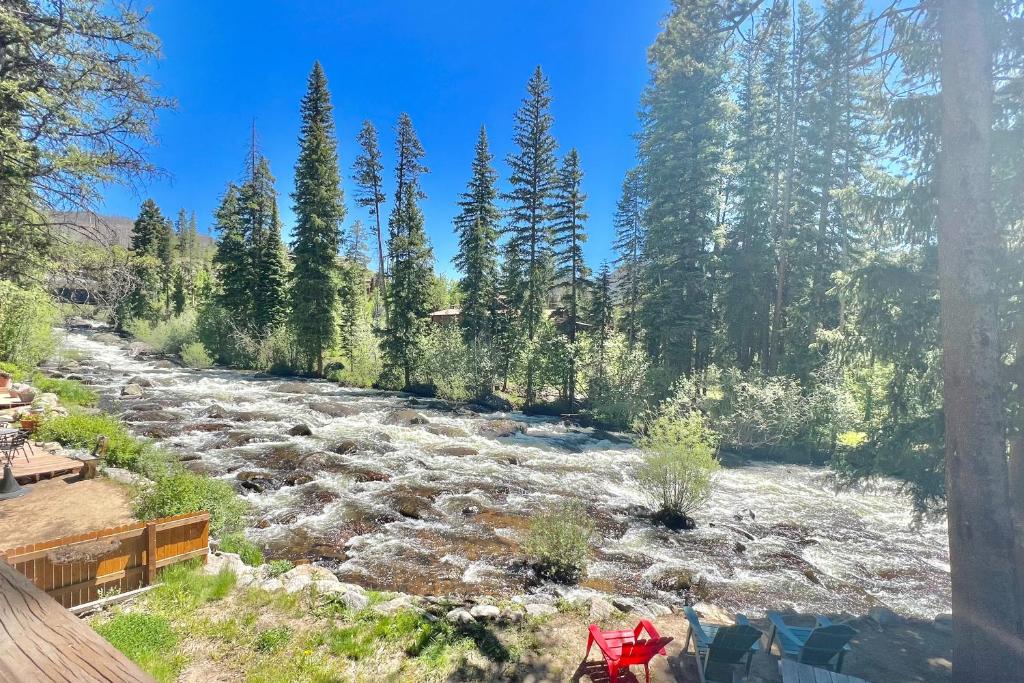 a river with trees and a red bike in the foreground at On the Rapids - B Unit in Grand Lake