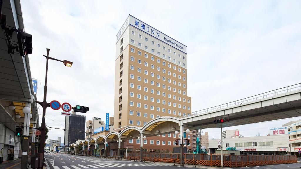 un edificio alto en una calle de la ciudad con un puente en Toyoko Inn Iwakuni eki Nishi guchi, en Iwakuni