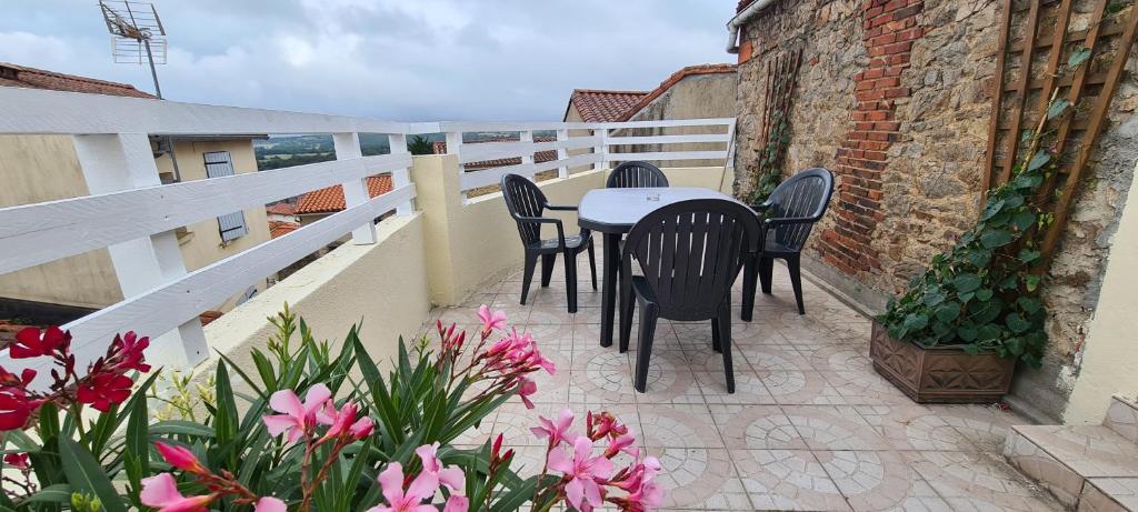 una mesa y sillas en un balcón con flores en Gîte Le Bocage à 4 min du Puy du Fou, en Les Épesses
