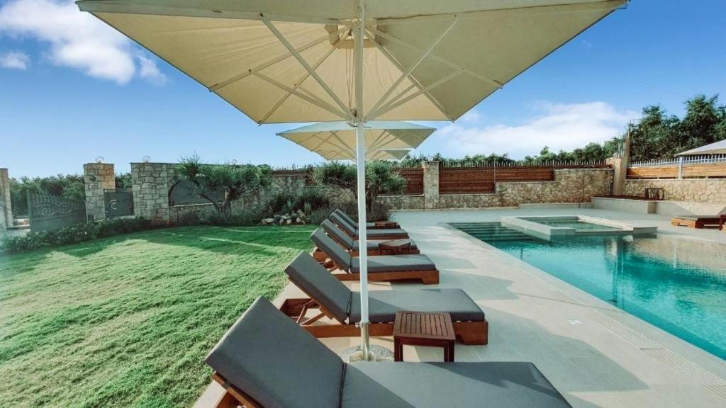 a swimming pool with lounge chairs and an umbrella at Entheon Olive Villas - Poolside Retreats in Marathopoli