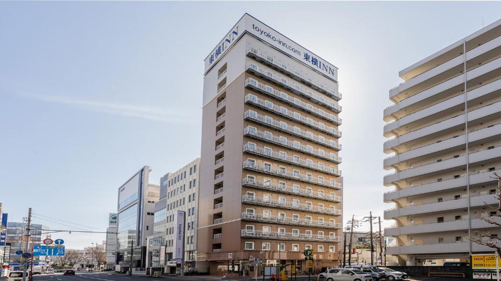 un edificio blanco alto en una calle de la ciudad en Toyoko Inn Shizuoka eki Kita guchi, en Shizuoka