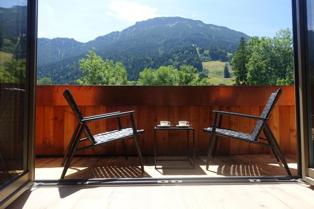 Duas cadeiras e uma mesa numa varanda com montanhas em Alpinchalet em Pfronten