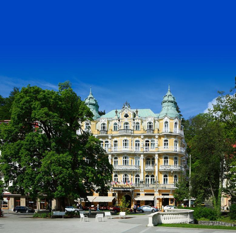 マリアーンスケー・ラーズニェにあるOREA Spa Hotel Bohemia Mariánské Lázněの目の前に木が立つ大きな黄色の建物