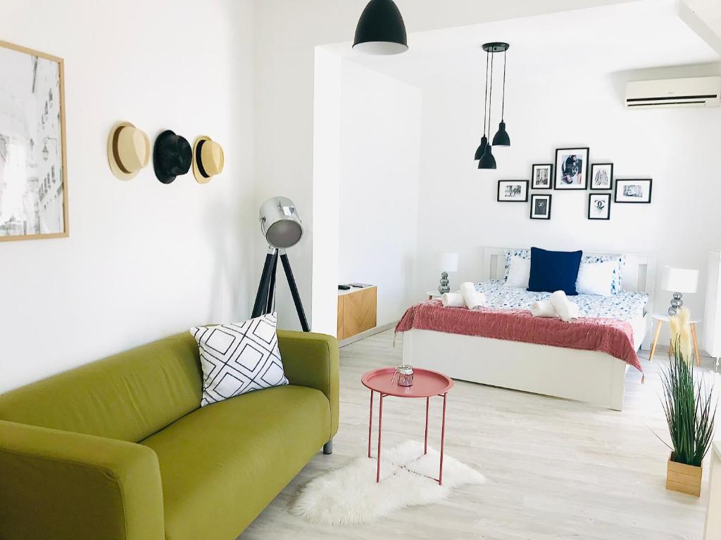 a living room with a green couch and a bed at Belvárosi Stúdió Apartman in Kecskemét