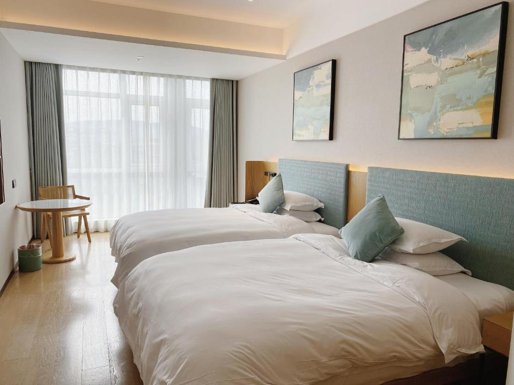 杭州市にあるSSAW Boutique Hotel Zhijiangのベッド2台と窓が備わるホテルルームです。