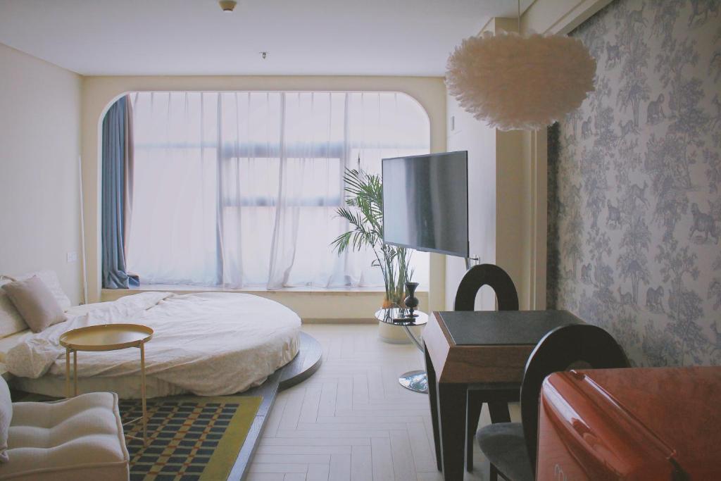 a bedroom with a bed and a desk and a window at Amyitis Sky Garden - Located in the heart of Wulin with a view of Hangzhou West Lake in Hangzhou