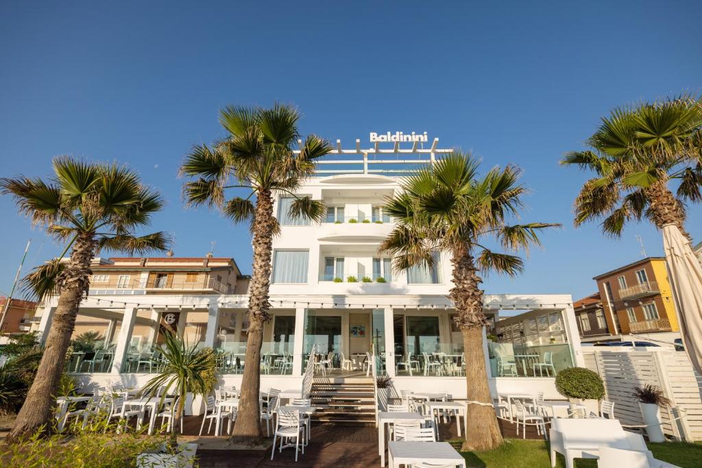 um edifício branco com palmeiras em frente em Baldinini Hotel em Rimini