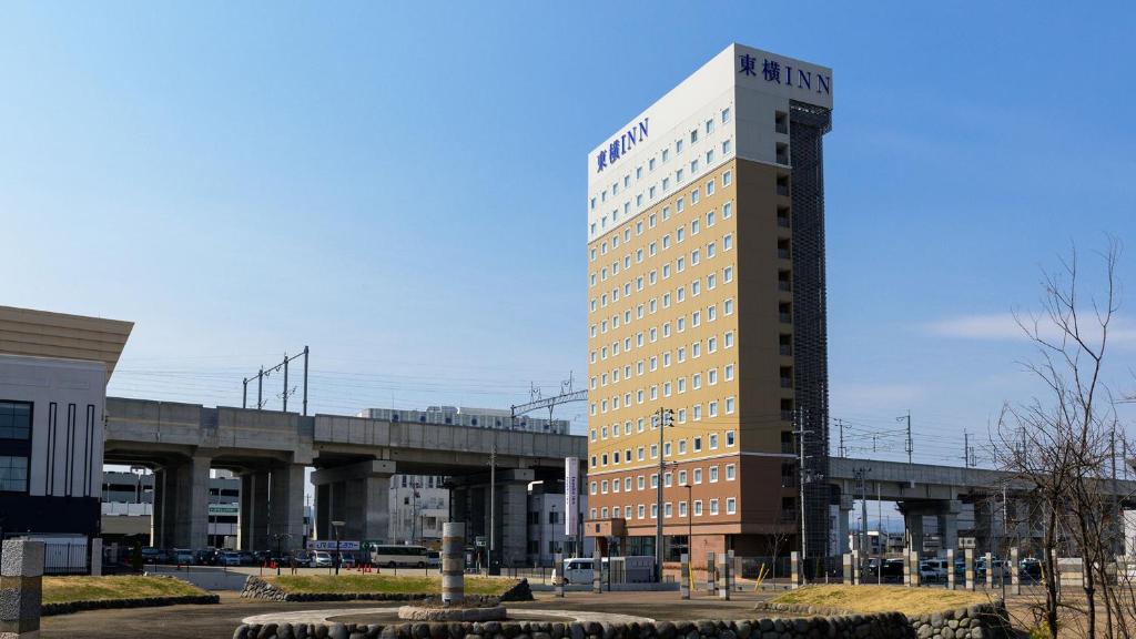 wysoki budynek z mostem w tle w obiekcie Toyoko Inn Shin-Aomori-eki Higashi-guchi w mieście Aomori
