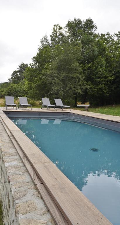 a swimming pool with two lounge chairs and a bench at Une pause en Corrèze in Sarroux