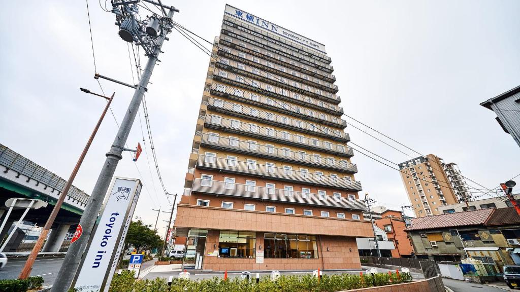 大阪的住宿－Toyoko Inn Osaka Kadoma-shi Ekimae，一座高大的建筑,旁边有一个标志