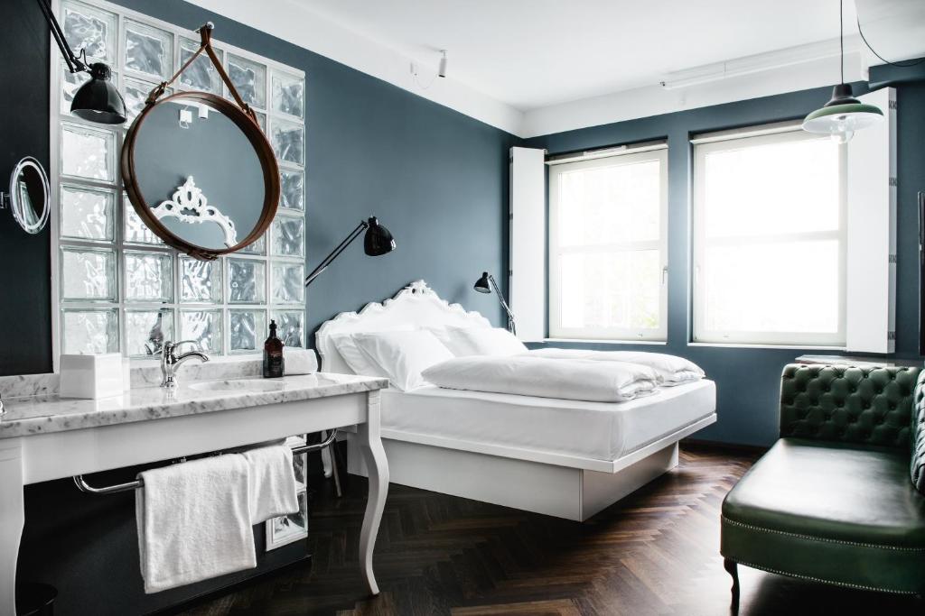 Dormitorio azul con cama y espejo en Grand Ferdinand Vienna – Your Hotel In The City Center, en Viena