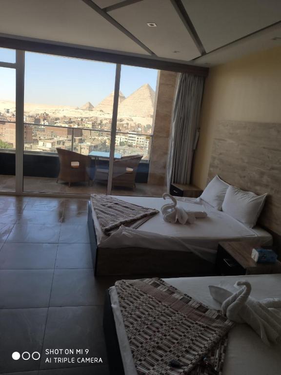 a hotel room with two beds and a view of the pyramids at pyramids view suite/vista piramidi in Cairo