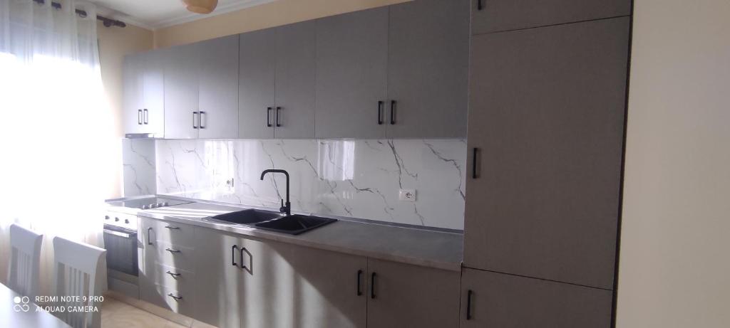 a kitchen with white cabinets and a sink at Guesthouse Isolde in Vlorë