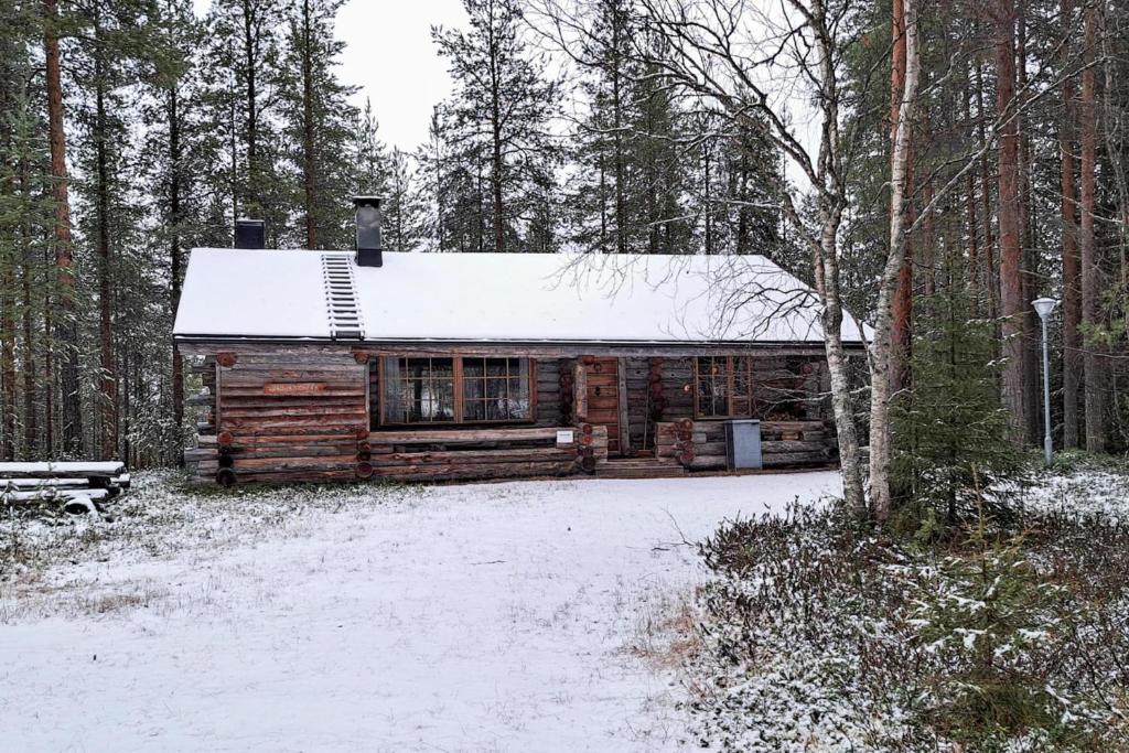 a log cabin with a snow covered roof in the woods at Kielaslinna above the Arctic Circle in Suomutunturi