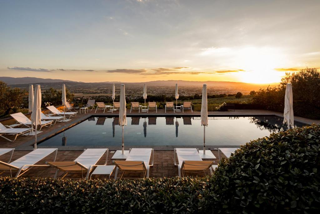 a swimming pool with lounge chairs and the sunset at La Quercetta in Foligno
