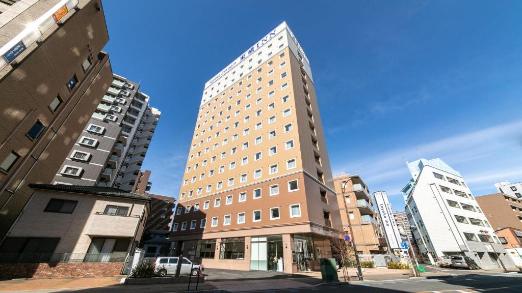 un edificio alto en una calle de la ciudad con edificios en Toyoko Inn Shiki eki Higashi guchi, en Shiki