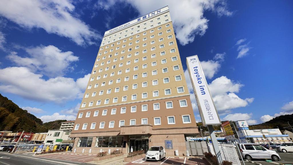 um edifício alto com um sinal em frente em Toyoko Inn Hamada eki Kita guchi em Hamada