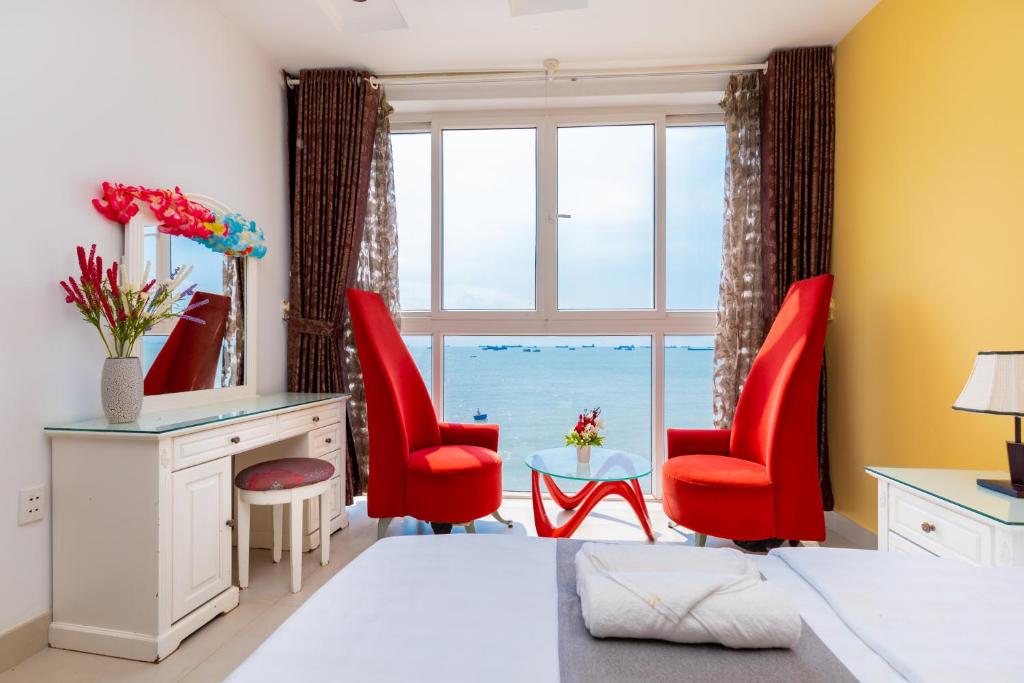 een slaapkamer met rode stoelen, een bureau en een raam bij Palm Villa 22 - Ocean View 3bedrooms in Vung Tau