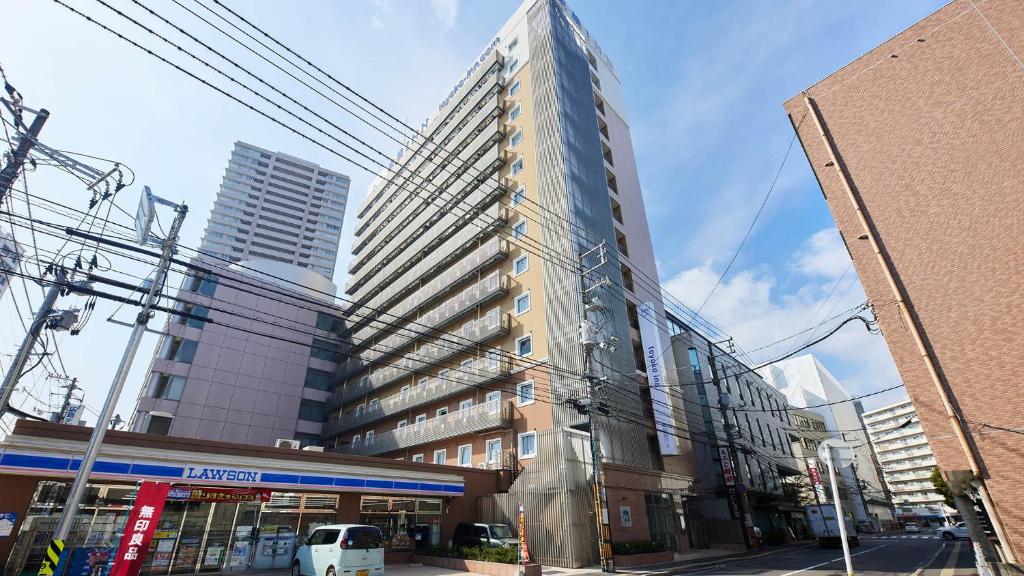 ein hohes Gebäude auf einer Straße in einer Stadt in der Unterkunft Toyoko Inn Hiroshima-eki Shinkansen-guchi No.2 in Hiroshima