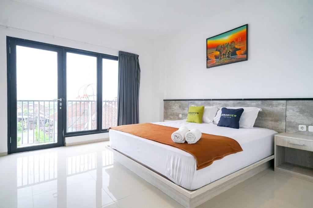 a bedroom with a large bed and a large window at Urbanview Pecatu Residence Bali by RedDoorz in Ungasan