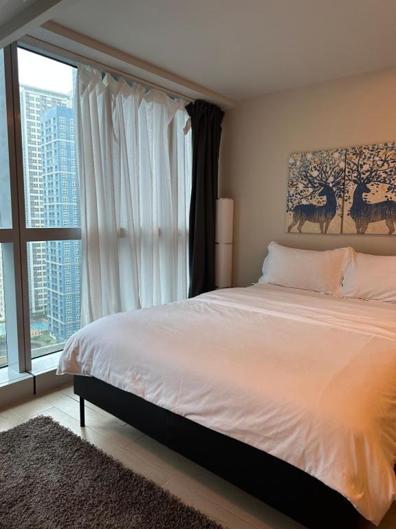 a bedroom with a bed and a large window at One Uptown Residence - Thompson Suites in Manila