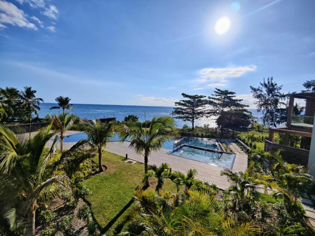 uma vista aérea de um resort com uma piscina e o oceano em Ocean Point Beach Front Apartment em Pointe aux Piments