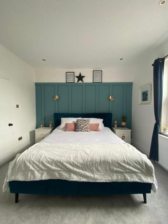 a bedroom with a large bed with a blue headboard at Luxury Spacious Renovated Townhouse in Grantham