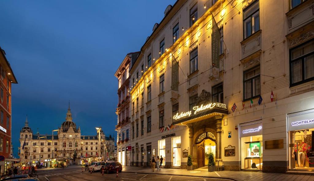 a city street at night with buildings and people at Palais-Hotel Erzherzog Johann in Graz