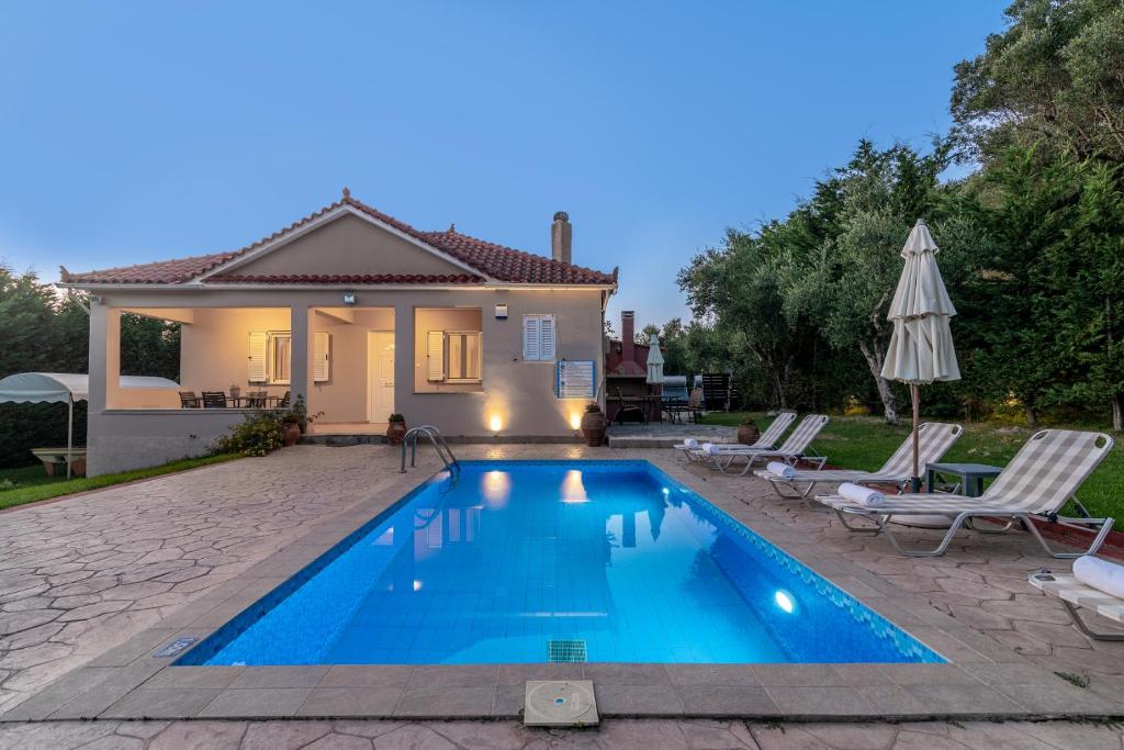 a swimming pool in front of a house at Planos Villa in Tsilivi