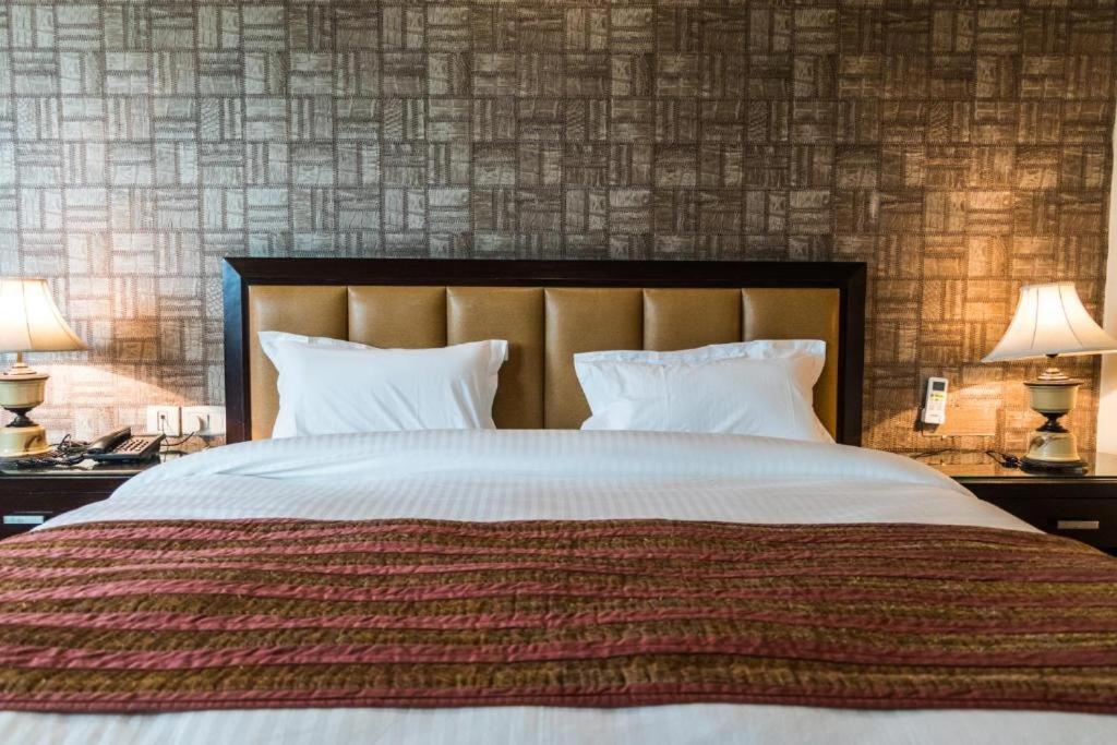 una camera con un grande letto con due lampade sui tavoli di IKHAYA HOTELS a Nuova Delhi