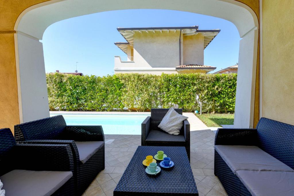 eine Terrasse mit Stühlen, einem Tisch und einem Pool in der Unterkunft Villa Iris in Manerba del Garda