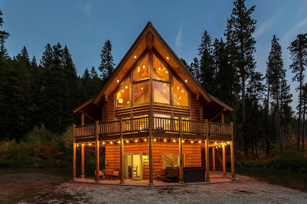 a log cabin in the woods with lights on at Bearfoot Chalet by NW Comfy Cabins in Leavenworth