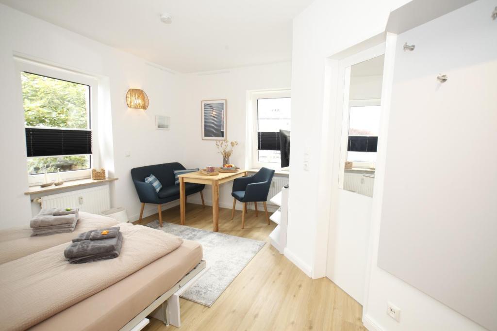 a white room with a bed and a table and chairs at Kapitän's Koje Wangerooge in Wangerooge