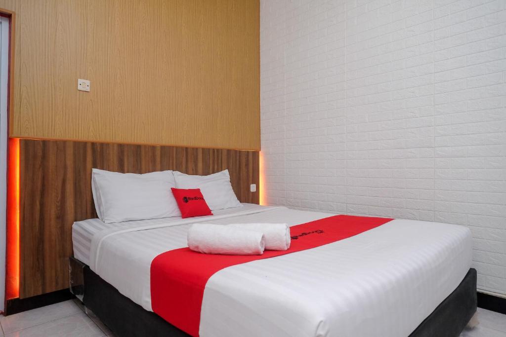 1 dormitorio con 1 cama blanca grande con manta roja en RedDoorz At Pondok Eyang Obi Sleman en Yogyakarta