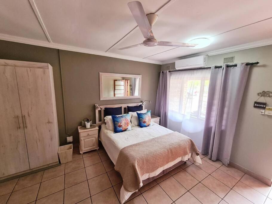 1 dormitorio con 1 cama y ventilador de techo en Flamboyant Apartments, en St Lucia