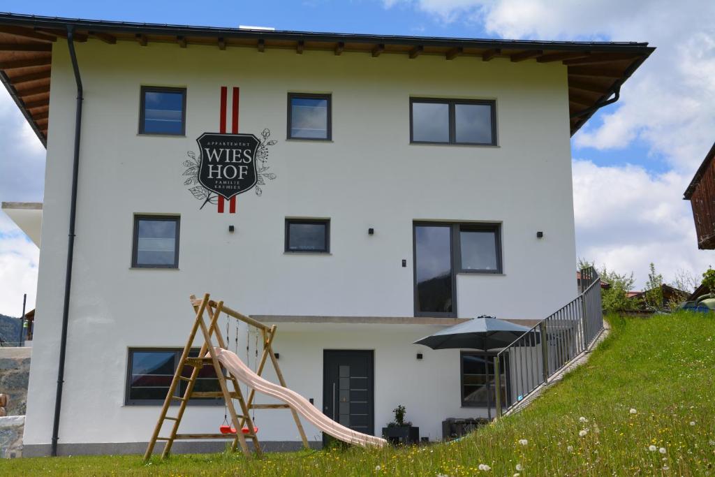 a white house with a playground in front of it at Appartement Wieshof in Neukirchen am Großvenediger