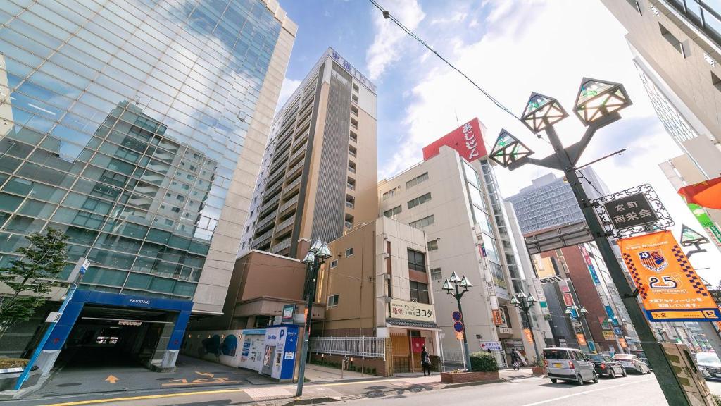 una calle de la ciudad con edificios altos y luz de la calle en Toyoko Inn Omiya-eki Higashi-guchi en Saitama