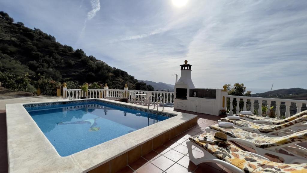 une piscine avec des chaises longues et un phare dans l'établissement Villa Paco At Home, à Torrox