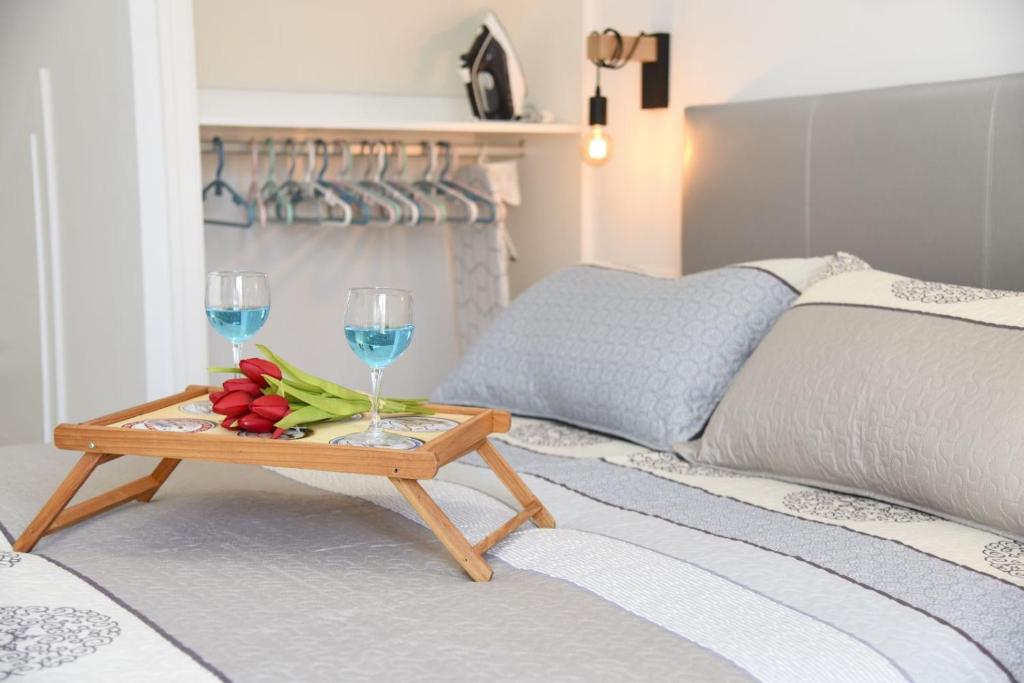 a tray with two wine glasses and flowers on a bed at Estudio Platero in Nerja