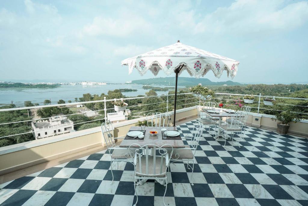 a patio with a table and an umbrella on a balcony at Burj Baneria in Udaipur