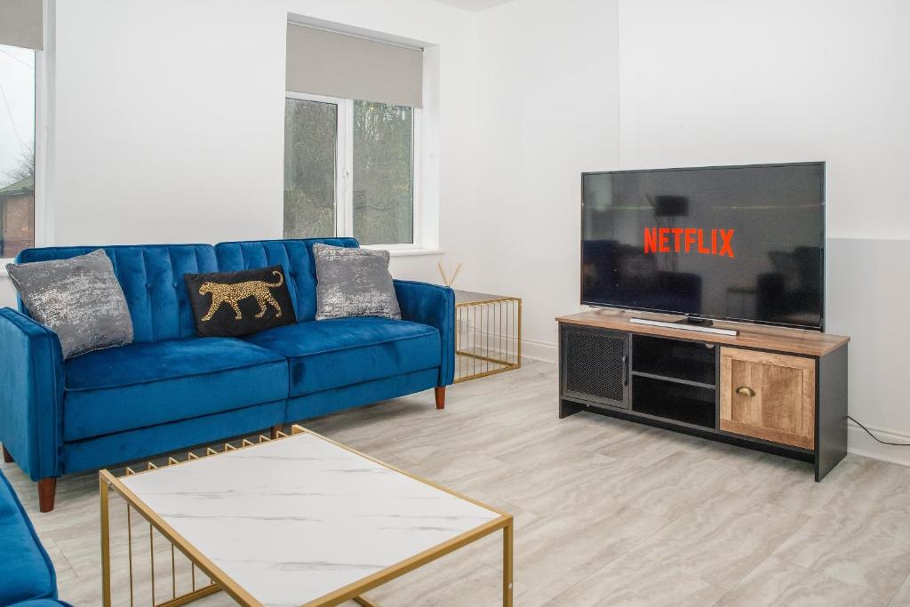 a living room with a blue couch and a tv at K Suites - 112 Fulbridge Road OLD in Peterborough