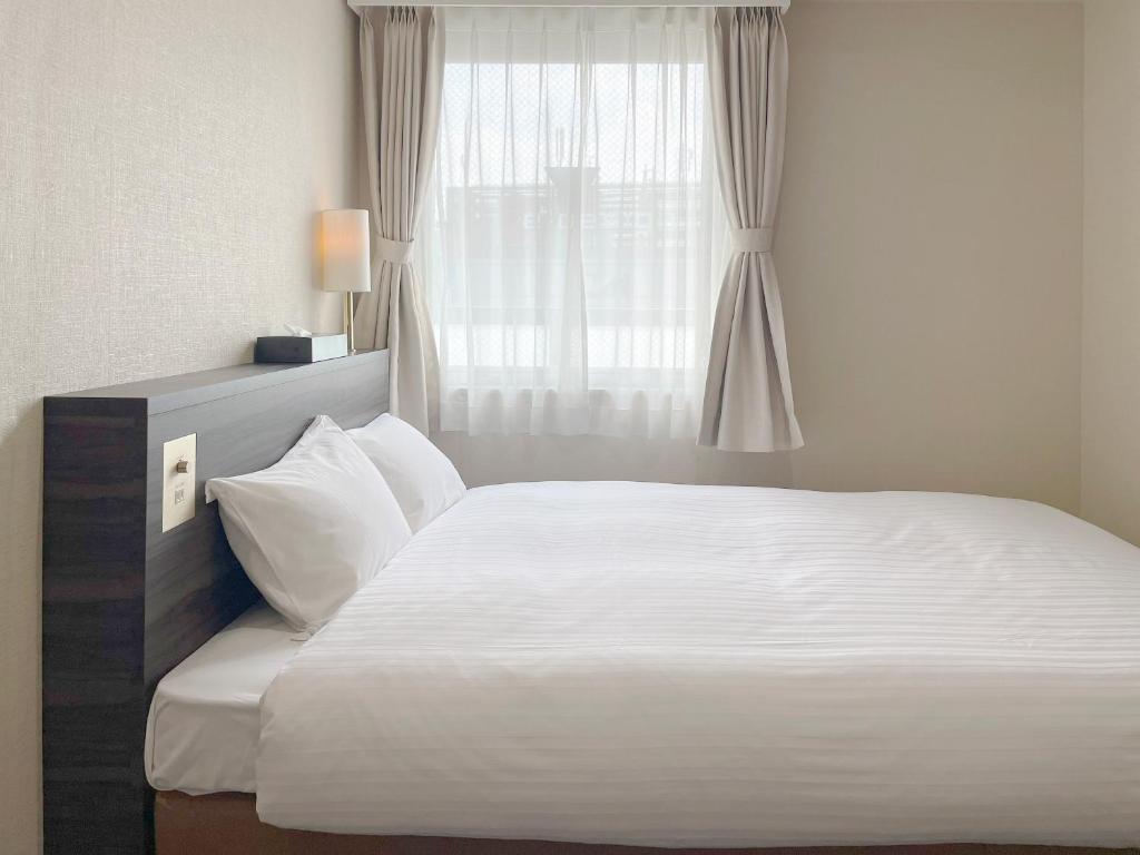 Postel nebo postele na pokoji v ubytování CHECKinn Osaka Shinimamiya