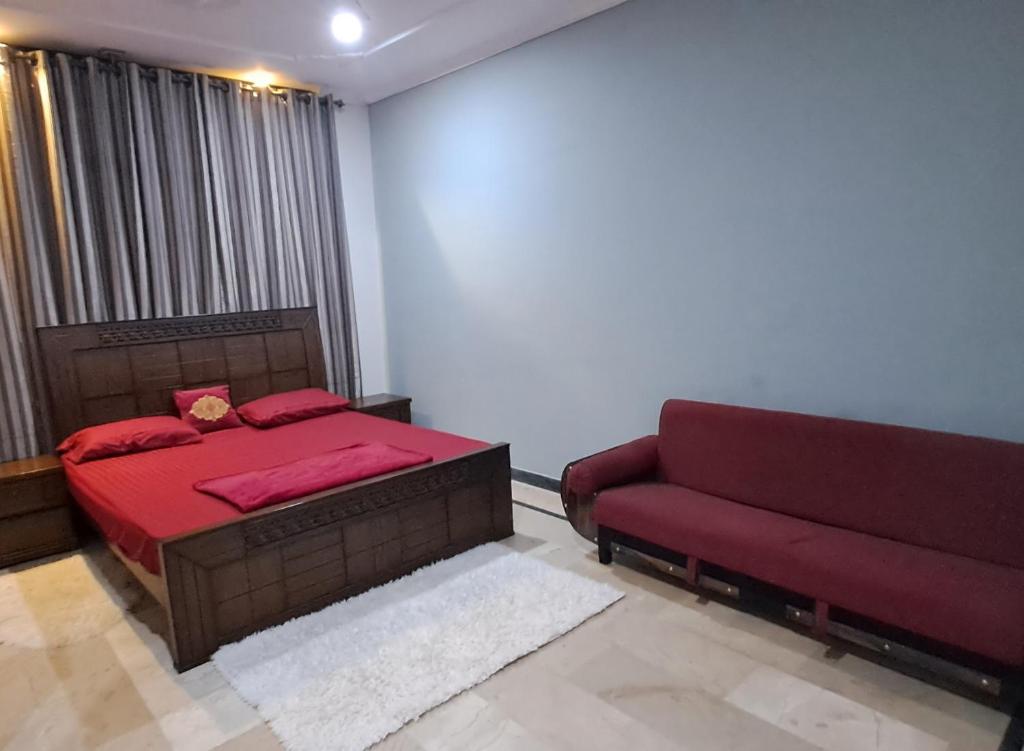 a bedroom with a red bed and a couch at Islamabad Airport Guest House Free Pick-up and Drop off Available 24 Hours in Islamabad