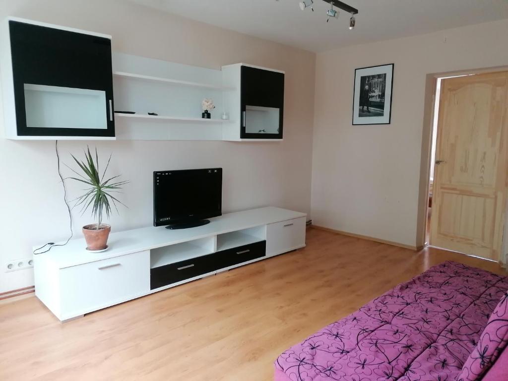 een witte woonkamer met een tv en een bed bij City Center Holiday Apartments in Liepāja