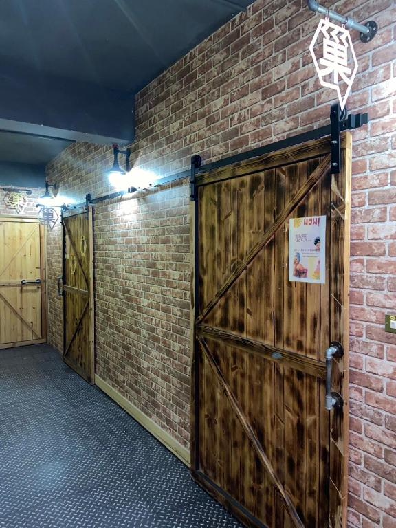 a room with two wooden doors and a brick wall at Hive Bed and Backpacker蜂巢膠囊旅店 in Hualien City