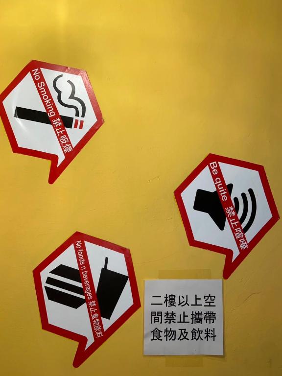 a group of signs on a yellow wall at Hive Bed and Backpacker蜂巢膠囊旅店 in Hualien City