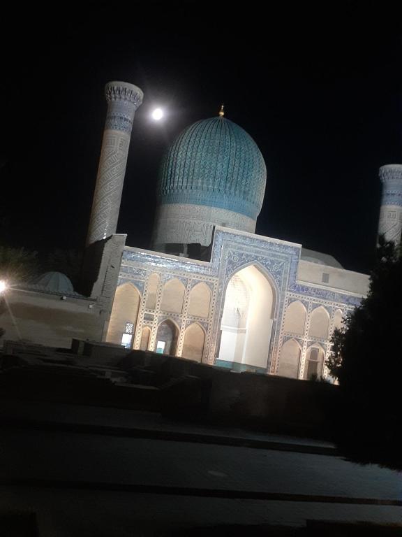 a mosque with a blue dome on top at night at Hotel Dilnura in Samarkand